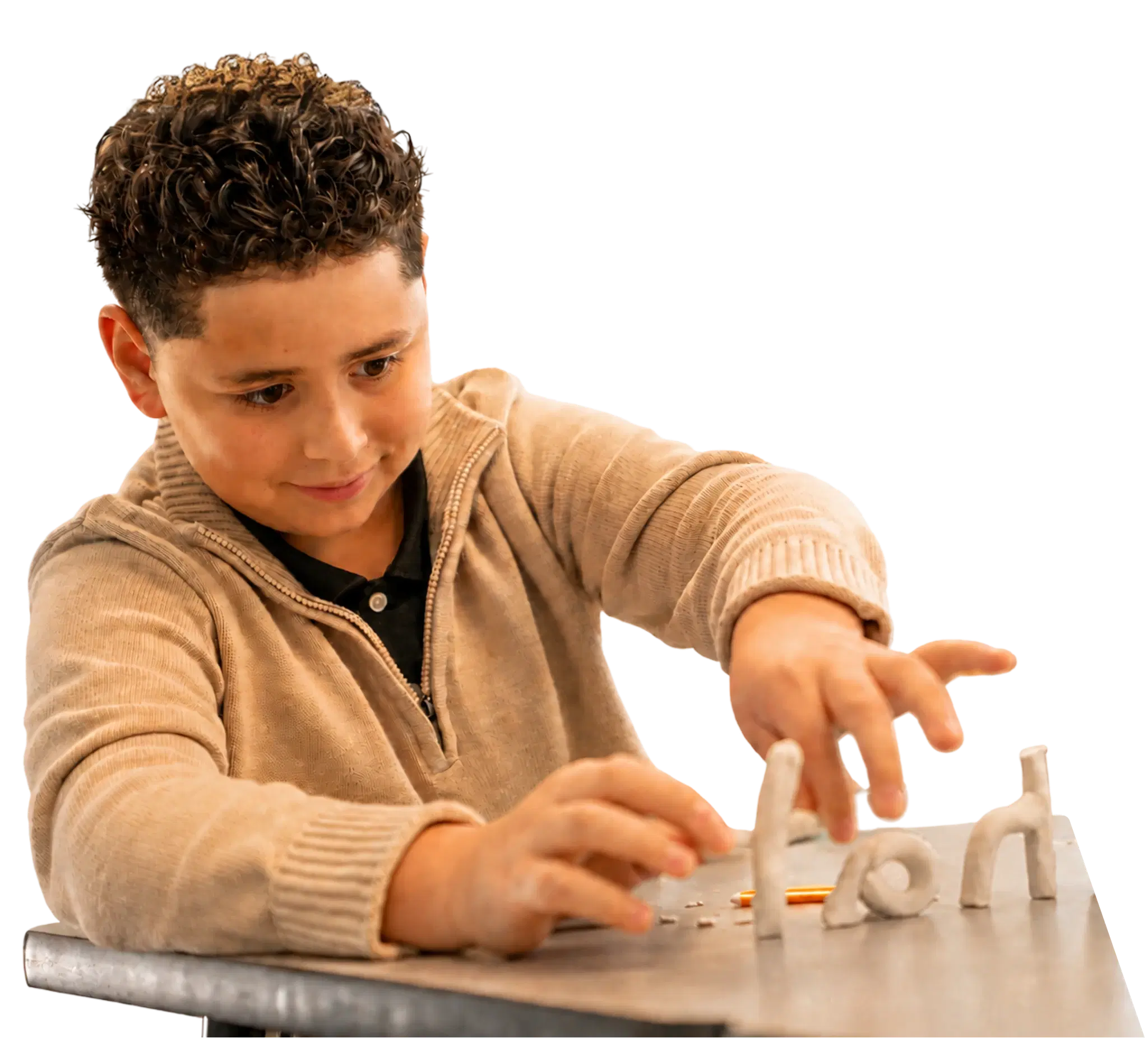A child placing clay letters on a desk to build a word