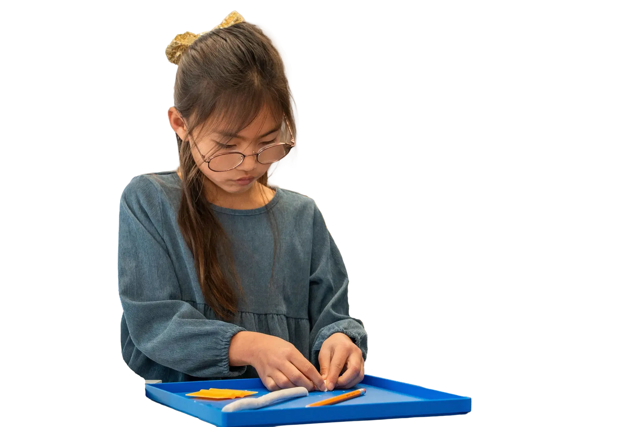 A child shaping clay letters on a tray